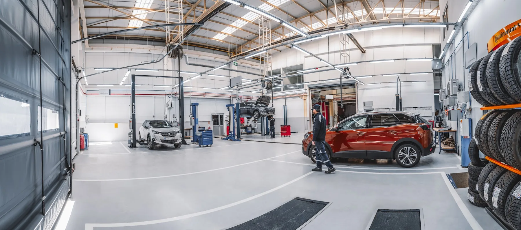 Helle, moderne Kfz-Werkstatt mit Fahrzeugen auf der Hebebühne
